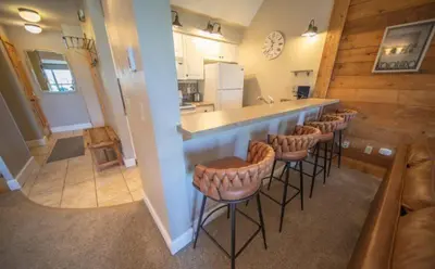 a kitchen with a bar and a bunch of stools at 1 Bedroom Mountain Condo In Lakeside Village Near Keystone Lake With Complimentary Shuttle Service in Keystone