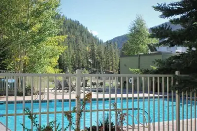 a fence next to a swimming pool with trees at 1 Bedroom Mountain Condo In Lakeside Village Near Keystone Lake With Complimentary Shuttle Service in Keystone