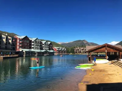 a person is standing on a paddle board in the water at Luxury 3 Bedroom Townhouse Next To Keystone Lake, Free Shuttle, Hot Tub And Sauna in Keystone