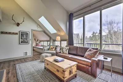 a living room with a brown leather couch and large windows at Hot Tub and Ski Shuttle Access Keystone Condo! in Keystone