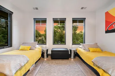 two beds in a room with windows at Relaxing in Paradise with Private Rooftop Deck! in Fort Collins