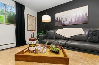 a living room with a couch and a table with a bottle of alcohol at Contemporary condo in the heart of Old Town in Fort Collins