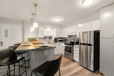 a kitchen with white cabinets and a stainless steel refrigerator at Stunning Downtown Condo - 5 min walk to Old Town! in Fort Collins