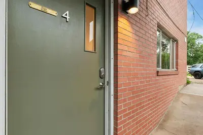 a green door on the side of a brick building at Stunning Downtown Condo - 5 min walk to Old Town! in Fort Collins