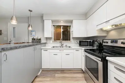 a kitchen with white cabinets and a sink at Stunning Downtown Condo - 5 min walk to Old Town! in Fort Collins