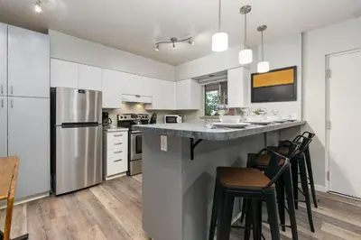 a kitchen with white cabinets and a counter with stools at Stylish Condo in the Heart of Old Town in Fort Collins