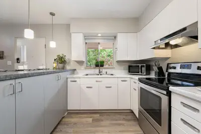 a kitchen with white cabinets and a sink at Old Town Condo by Library Park Walk Everywhere! in Fort Collins