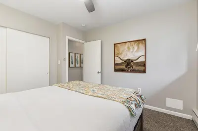 a bedroom with a bed and a picture of a cow at Gorgeous Condo in the Heart of Old Town in Fort Collins