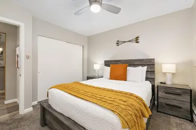 a bedroom with a large bed with an orange blanket at Gorgeous Condo in the Heart of Old Town in Fort Collins