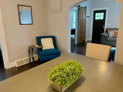 a living room with a table and chairs and a mirror at The Cottage! Chic Bungalow near Old Town Square! in Fort Collins