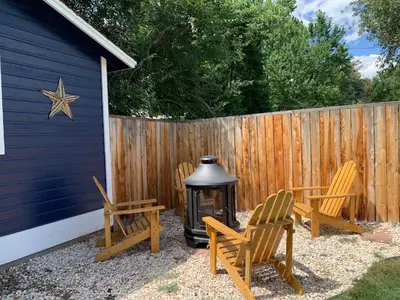 a backyard with two chairs and a grill and a fence at The Cottage! Chic Bungalow near Old Town Square! in Fort Collins