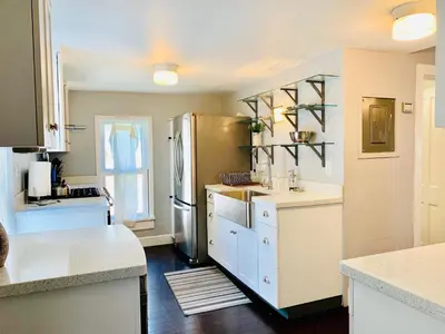 a kitchen with a stainless steel refrigerator and white cabinets at The Cottage! Chic Bungalow near Old Town Square! in Fort Collins