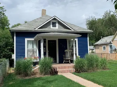 a blue house with a chair on the front porch at The Cottage! Chic Bungalow near Old Town Square! in Fort Collins