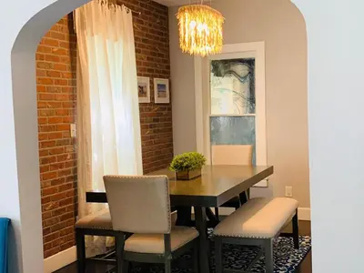a dining room table with chairs and a chandelier at The Cottage! Chic Bungalow near Old Town Square! in Fort Collins