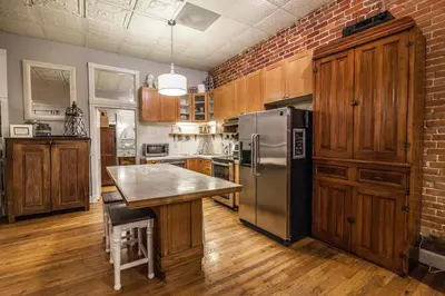 a kitchen with a brick wall and a stainless steel refrigerator at Elegant Loft-Style Retreat in Old Firehouse Alley in Fort Collins