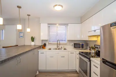 a kitchen with white cabinets and a sink at Hip & Urban Condo near the Heart of Old Town in Fort Collins