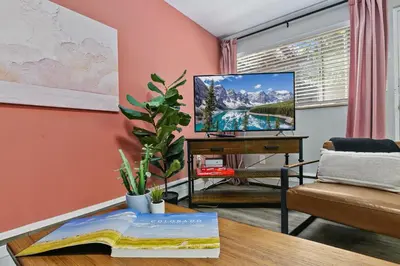 a living room with a tv and a table with a book at Hip & Urban Condo near the Heart of Old Town in Fort Collins