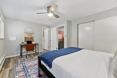 a white bedroom with a bed and a desk at Hip & Urban Condo near the Heart of Old Town in Fort Collins