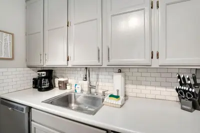 a kitchen counter with a sink and white cabinets at Charming Old Town Bungalow with Free Cruiser Bikes in Fort Collins