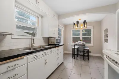 a white kitchen with a sink and a table at Beautiful Bungalow Next to CSU, Free Cruiser Bikes in Fort Collins