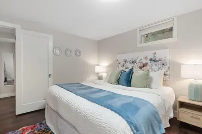 a white bedroom with a large bed with blue accents at Charming Bungalow Next to CSU - Free Cruiser Bikes in Fort Collins