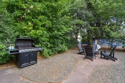 a backyard with a grill and chairs and trees at Charming Bungalow Next to CSU - Free Cruiser Bikes in Fort Collins