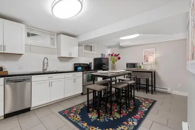 a kitchen with white cabinets and a table with stools at Charming Bungalow Next to CSU - Free Cruiser Bikes in Fort Collins