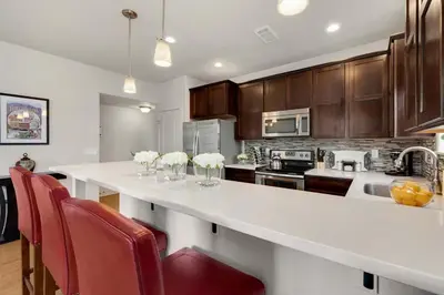 a kitchen with a white counter and red chairs at Modern Townhome Steps from the Brewery District! in Fort Collins