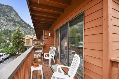 a balcony with white chairs on a wooden house at Cedar Lodge 221 condo in Frisco