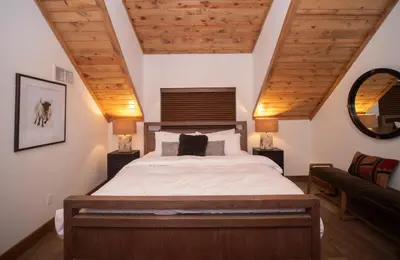 a bedroom with a large bed with wooden ceilings at Rocky Mountain Escape - Steps to Lake Estes, Jacuzzi, Close to Downtown Estes in Estes Park