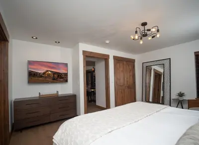 a bedroom with a white bed and a chandelier at Estes Escape – Jacuzzi, Indoor/Outdoor Fireplace and BBQ Grill in Estes Park