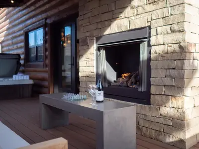 a fireplace in a patio with a table and wine glasses at Estes Escape – Jacuzzi, Indoor/Outdoor Fireplace and BBQ Grill in Estes Park