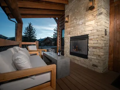 a bedroom with a fireplace on a deck with a bed at Lake Estes Getaway – Close to Downtown, Indoor/Outdoor Fireplace and Jacuzzi in Estes Park
