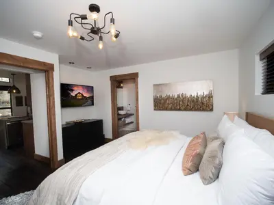 a bedroom with a white bed and a chandelier at Lake Estes Getaway – Close to Downtown, Indoor/Outdoor Fireplace and Jacuzzi in Estes Park