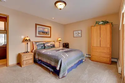 a bedroom with a bed and a wooden cabinet at Deck and Mtn View Keystone Townhome Near Resort! in Keystone