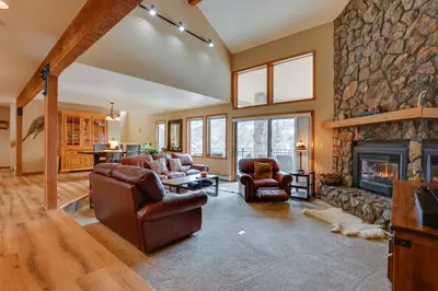 a living room with couches and a stone fireplace at Deck and Mtn View Keystone Townhome Near Resort! in Keystone