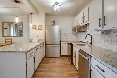 a kitchen with white cabinets and a stainless steel refrigerator at Walk to Ski Shuttle Cozy Mountain Meadows Condo in Frisco