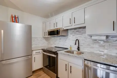 a kitchen with white cabinets and a stainless steel refrigerator at Walk to Ski Shuttle Cozy Mountain Meadows Condo in Frisco