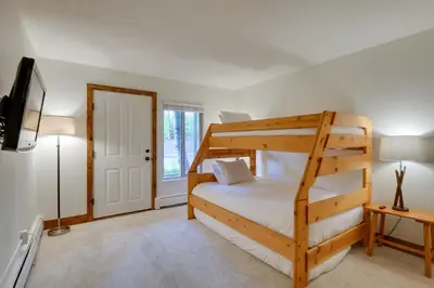 a bedroom with a bunk bed and a tv at Walk to Ski Shuttle Cozy Mountain Meadows Condo in Frisco