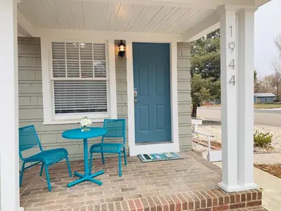a table and chairs on a porch with a blue door at Stunning Bungalow next to UNC - Free Bikes! in Greeley