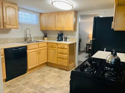 a kitchen with wooden cabinets and a black stove top oven at Inviting Bungalow Next to UNC - Free Cruiser Bikes in Greeley