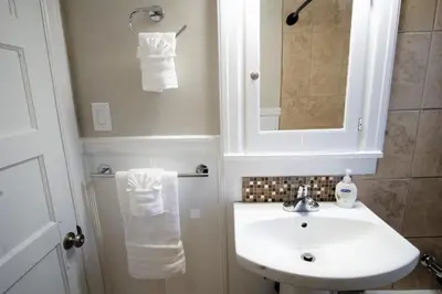 a white bathroom with a sink and a mirror at Beautiful Bungalow Next to UNC - Free Cruiser Bikes! in Greeley