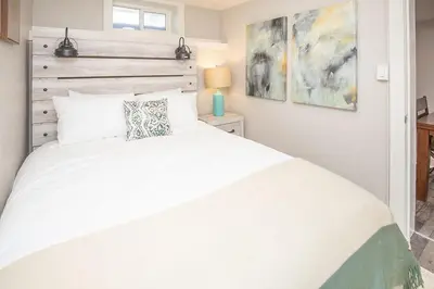 a bedroom with a white bed with a wooden headboard at Cozy Retreat - Walk to UNC - Free Cruiser Bikes in Greeley