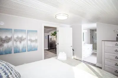 a white bedroom with a bed and a bathroom at Couples Getaway - Walk to UNC - Free Cruiser Bikes in Greeley