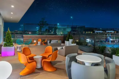 a rooftop patio with tables and chairs at night at Aloft Denver North Westminster in Westminster