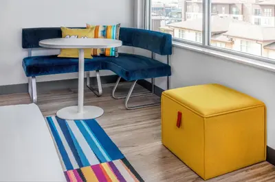 a room with a table and two chairs and a yellow stool at Aloft Denver North Westminster in Westminster