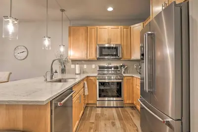 a kitchen with wooden cabinets and a stainless steel refrigerator at Fraser Retreat, Walk to Ski Shuttle and Main St in Fraser
