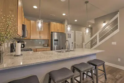 a kitchen with a counter with stools in it at Fraser Retreat, Walk to Ski Shuttle and Main St in Fraser