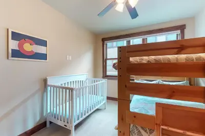 a bedroom with two bunk beds and a crib at Riverfront Retreat in Silverthorne