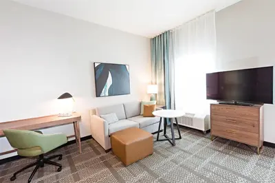 a hotel room with a couch and a desk and a tv at Staybridge Suites - Denver North - Thornton by IHG in Thornton